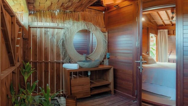 A wooden cabin with a round mirror, wooden bench, and a small sink. - Ecolodge Anacardier- Bungalow Deluxe 1 (Saint-Francois)