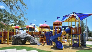 A playground with climbing structures, slides, and a rock feature.