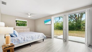 A bedroom with a bed, a window, a ceiling fan, and a view of the outdoors.