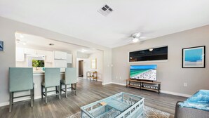 A modern living room with a dining area, a TV, and a ceiling fan.