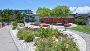 A landscaped area with a circular water feature, a red building, and a pathway.