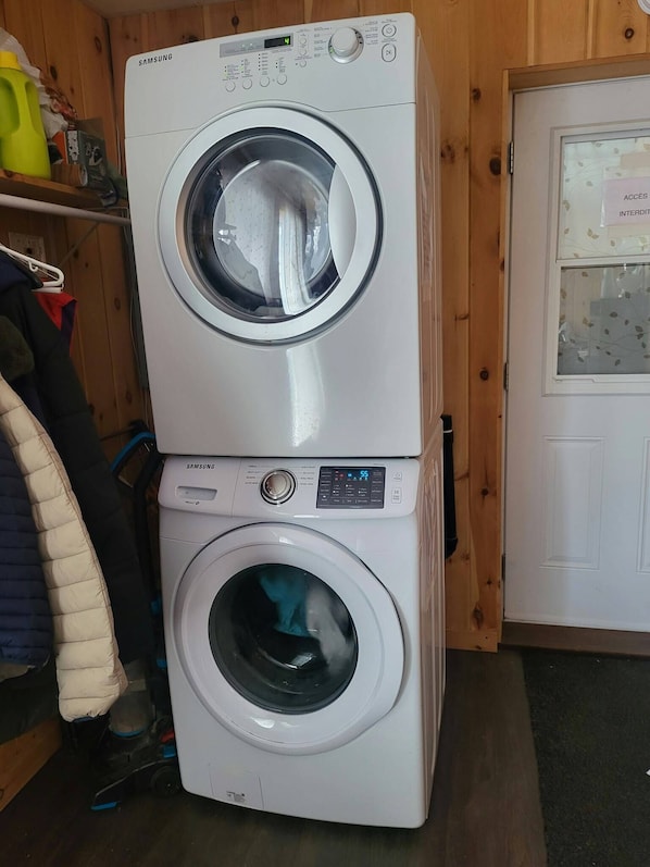 A stacked washer and dryer unit with a digital display, control panel, and a door with a frosted glass window.