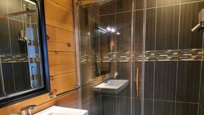 Ett modernt badrum med två tvättställ, en dusch och en duschhörna med glasväggar.