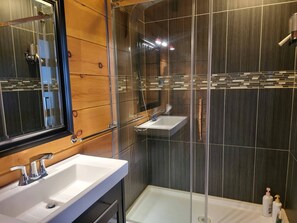 Un bagno moderno con due lavabi, una doccia e un box doccia in vetro.