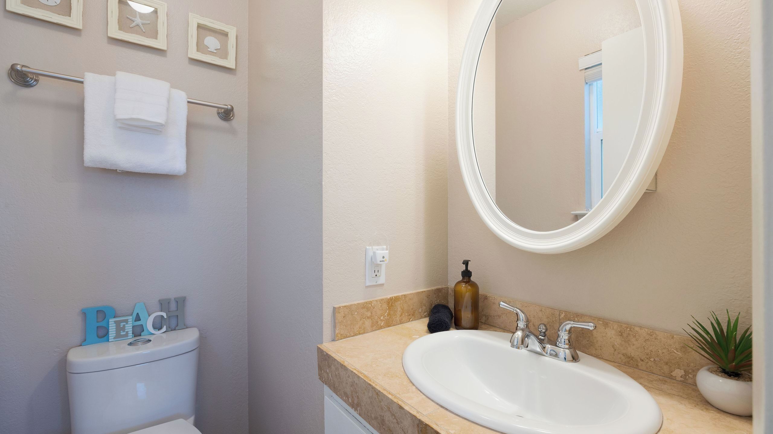 Een badkamer met toilet, wastafel, spiegel en handdoekhouder.