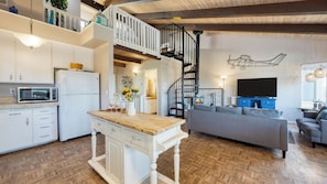 A modern kitchen with a microwave, white cabinets, and a wooden island. - Steps to Beach w/ Patio+deck Foosball Happy Bottom Beach House by Avantstay (Oceano)