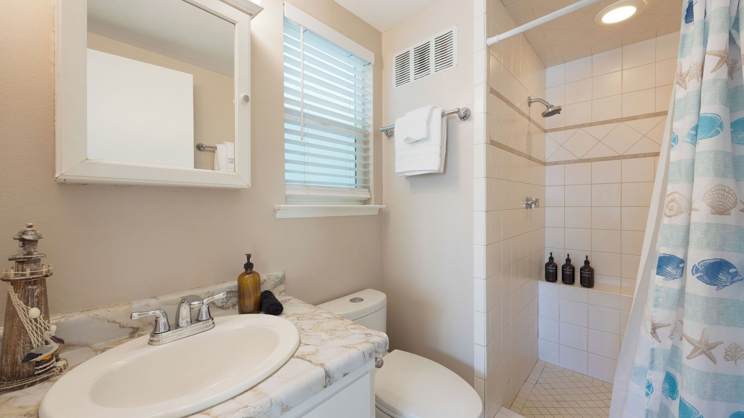 A bathroom with a sink, toilet, shower, and a mirror.