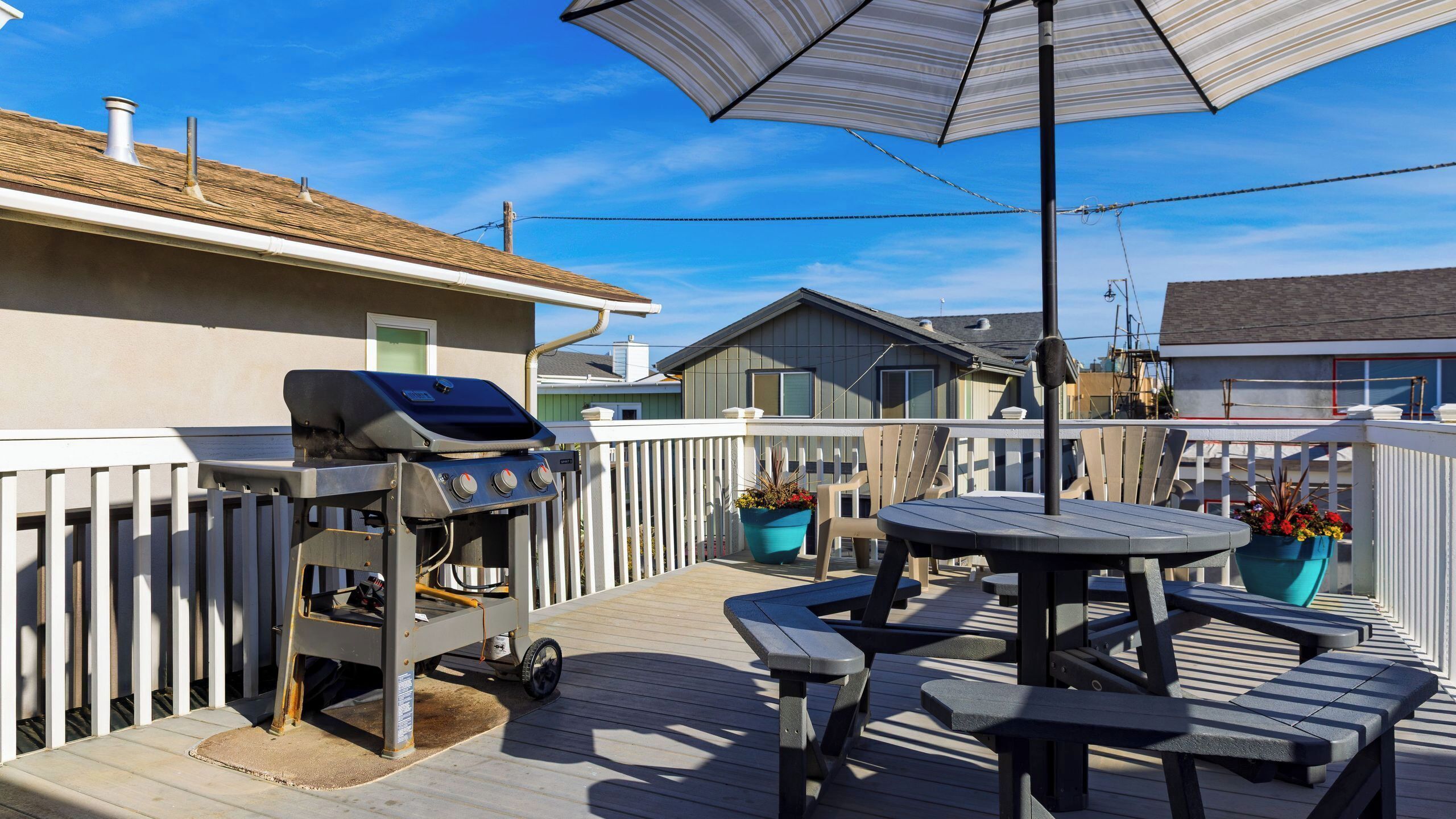 An outdoor patio with a grill, picnic table, and umbrella.
