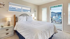 A bedroom with a bed, nightstands, a ceiling fan, and a view of the outside deck. - Steps to Beach w/ Patio+deck Foosball Happy Bottom Beach House by Avantstay (Oceano)