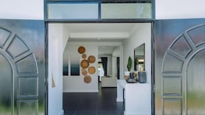 A modern interior with a hallway leading to a living area, featuring a unique wall art installation and a minimalist design. - Eden Villa A Tropical Paradise Pool Villa (Phuket)
