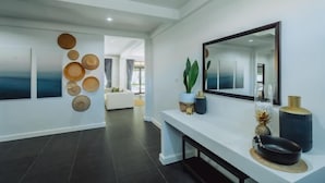 A modern interior with a white console table, a large mirror, and decorative wall art. - Eden Villa A Tropical Paradise Pool Villa (Phuket)