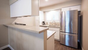 Eine moderne Küche mit einem Edelstahl-Kühlschrank, weißen Schränken und einer Arbeitsplatte.