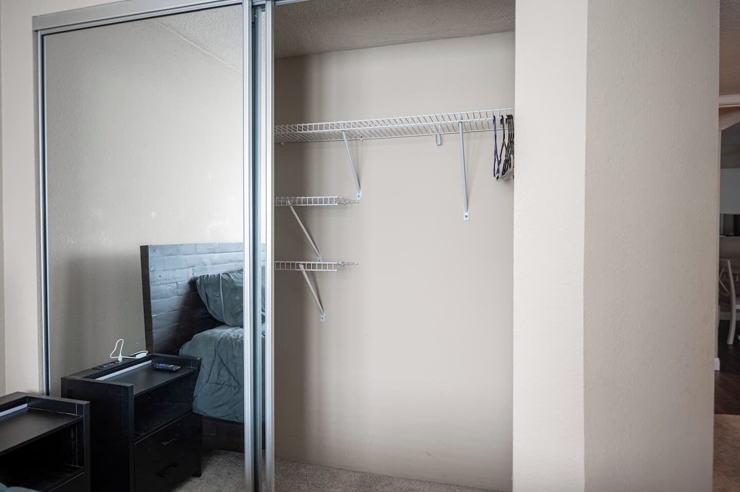 Ein Schlafzimmer mit einem Bett, einem Schreibtisch und einem Kleiderschrank mit Regalen.