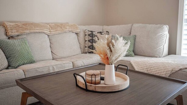 Ein Wohnzimmer mit einer Couch, einem Couchtisch und einer Vase mit Trockenblumen.