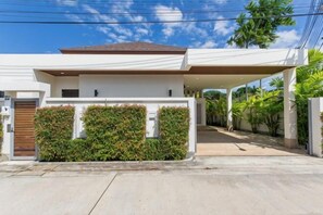 Een modern huis met een overdekte oprit, een hekpoort en een verzorgde tuin.