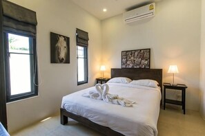 Een slaapkamer met een bed, twee bedlampjes, een wandairconditioner en een raam met gordijnen.