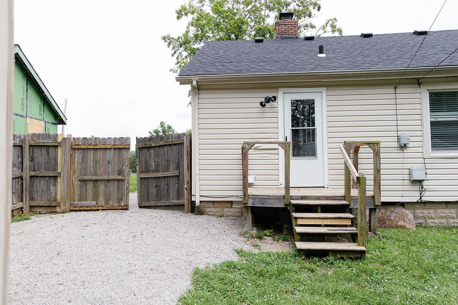 Een gelijkvloers huis met een voordeur, een klein portaal met treden en een houten hek.