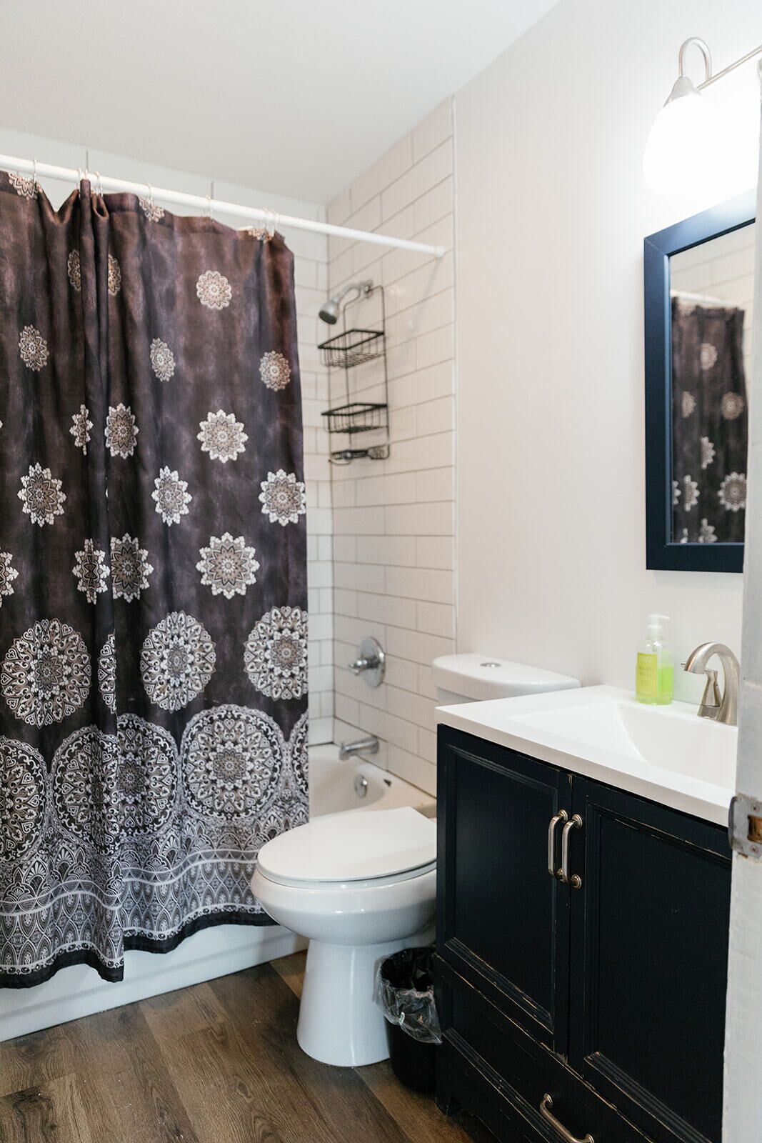 Een badkamer met douchegordijn, toilet, wastafel en spiegel.