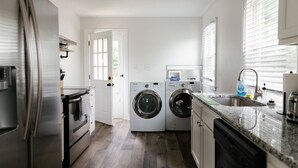 Une cuisine compacte équipée d’un réfrigérateur, d’un four, d’un lave-linge et d’un lave-vaisselle.