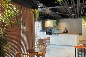A reception area with a counter, chairs, and a plant. - Airo Suites Makati (Makati)