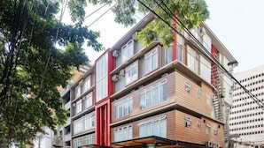 Un edificio de varios pisos con un diseño arquitectónico moderno, que combina fachadas de ladrillo y vidrio, y un llamativo detalle rojo en la planta baja.