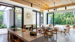 Una cocina moderna con una isla central, ventanas amplias y vistas a exuberante vegetación.