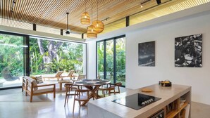 Una cocina moderna con una isla central, amplias ventanas y vistas a vegetación exuberante.