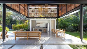 Un espace de restauration extérieur moderne, avec des meubles en bois et une cuisine en arrière-plan.