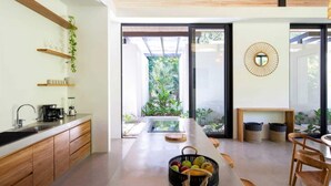 Une cuisine moderne avec des meubles en bois, une machine à café et un panier de fruits.