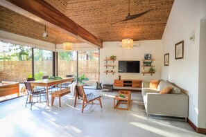 Relax in a spacious living area with a high ceiling, featuring a sofa, dining table, and flat-screen TV.