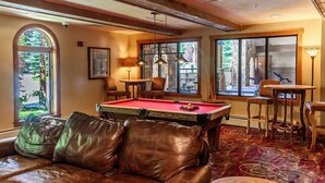 A pool table in a room with large windows, leather seating, and a view of the outdoors. - Slope-side Condo in Keystone (Keystone)