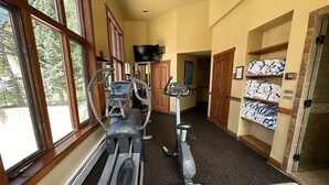 A gym with treadmills, an elliptical, and a stationary bike. There are large windows, wooden doors, and a tiled floor. - Slope-side Condo in Keystone (Keystone)