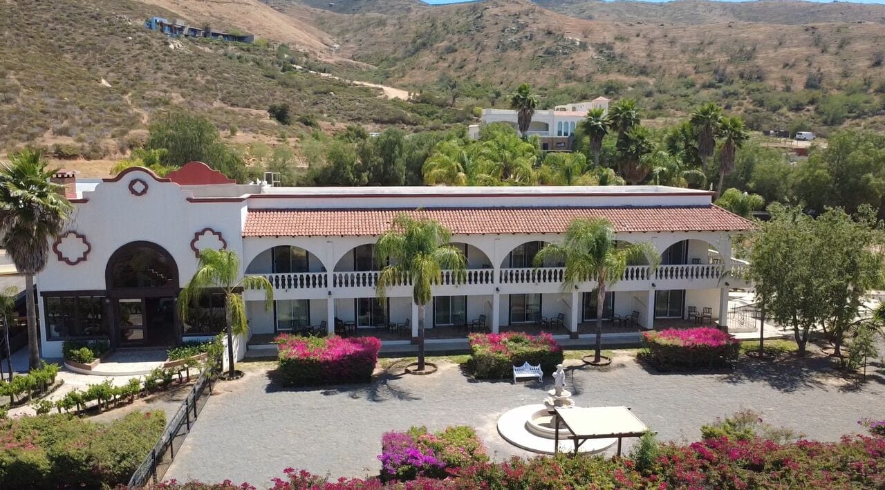 A hotel with a courtyard, palm trees, and a mountainous backdrop.