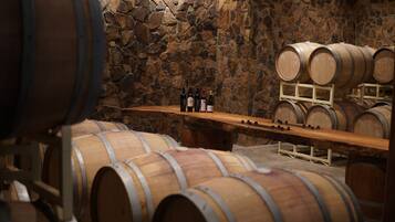 Des barriques en bois, dans une cave dont le mur est en pierre.