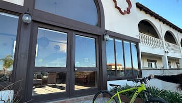 Un bâtiment doté d’une grande entrée en arc de cercle, avec un vélo garé devant et une terrasse carrelée.