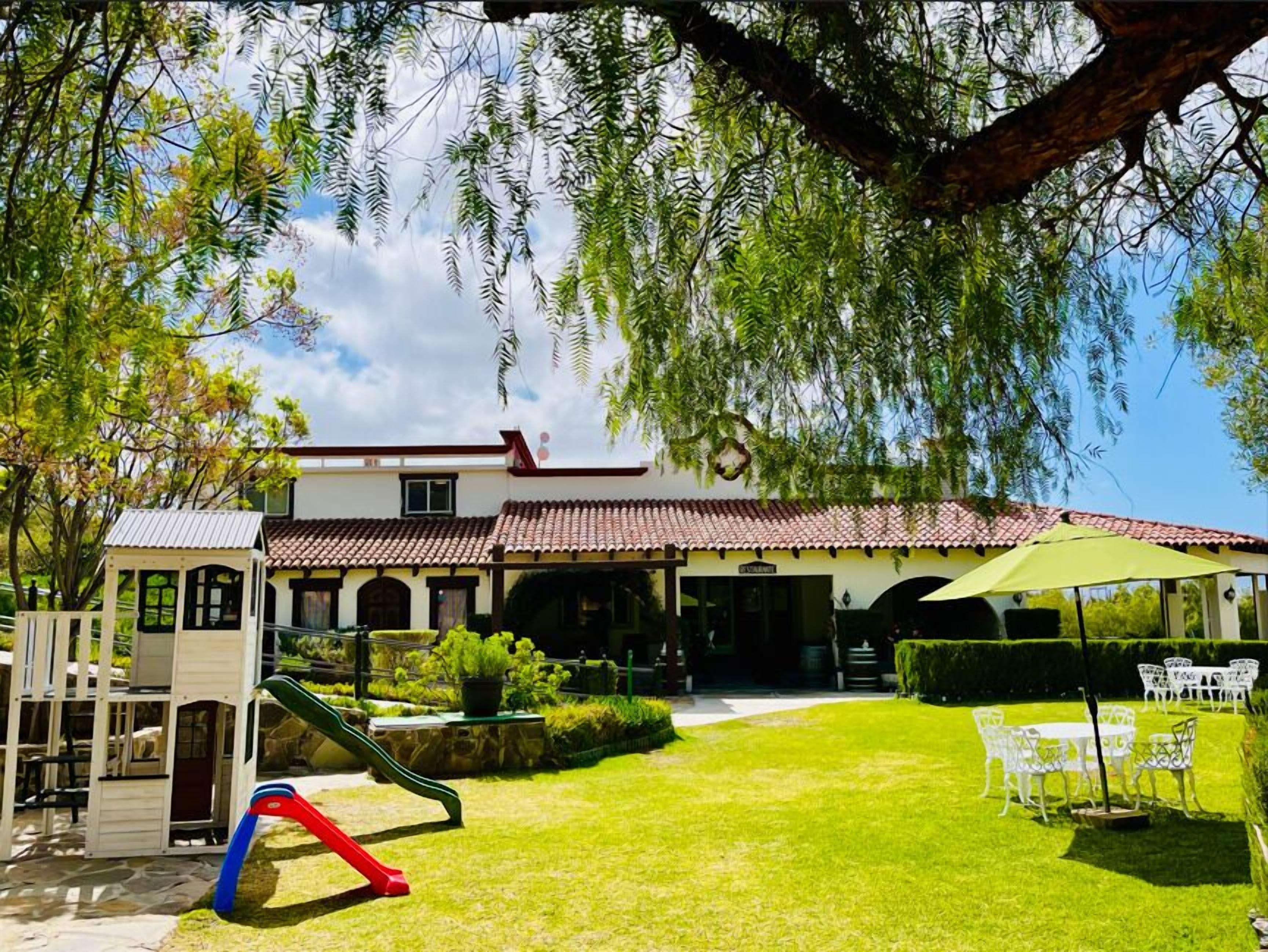 A house with a patio, a play area, and a lawn.