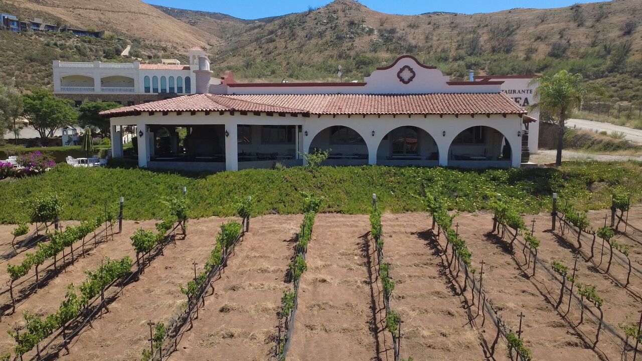 A building with a red-tiled roof, arched windows, and a sign that reads 'RESTAURANTE.'