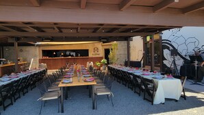 Una larga mesa de comedor con sillas, una zona de bar y un mural en la pared.