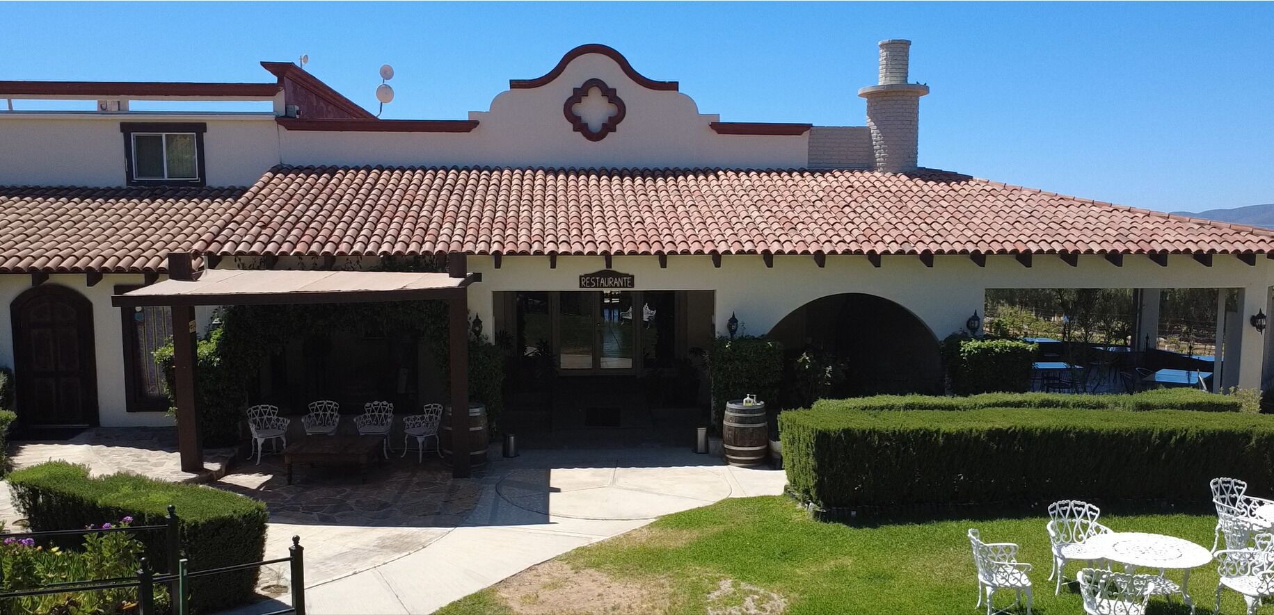 A restaurant with a tiled roof, outdoor seating, and a well-maintained garden.