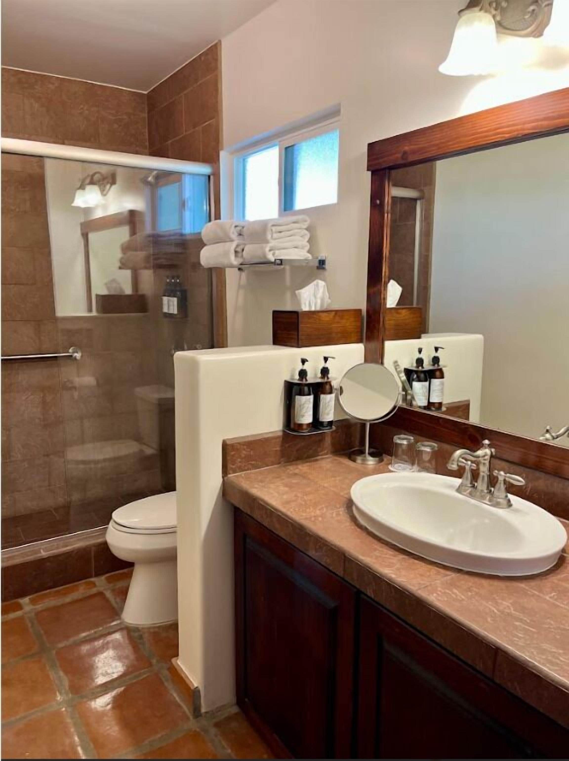 A modern bathroom with a glass shower enclosure, a white toilet, a sink with a mirror, and a towel rack.