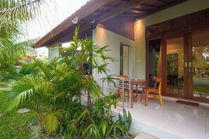 A modern house with a covered patio, a dining area, and a large sliding glass door. - Green Coconut Cottage Ubud (Bali)