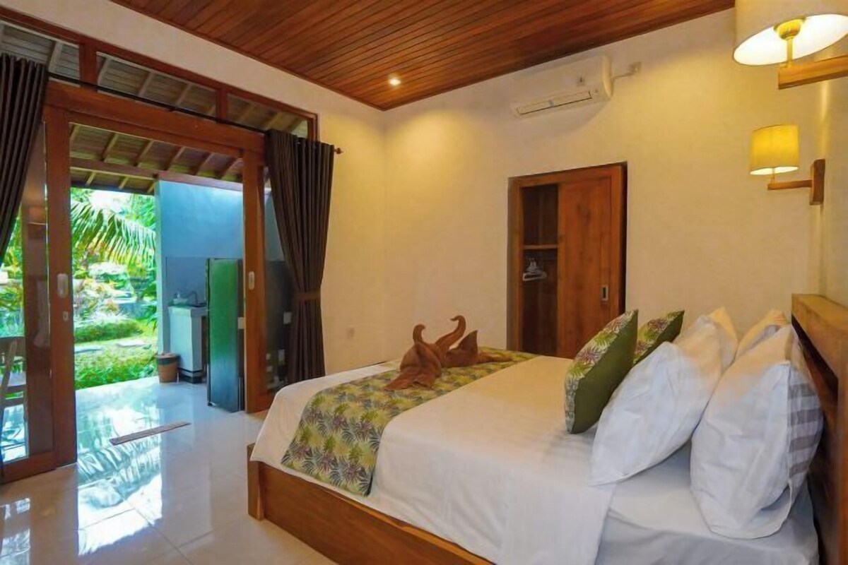 A bedroom with a bed, a wooden door, and a view of a garden.