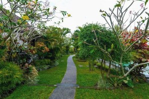 A pathway through a garden with various plants and trees. - Green Coconut Cottage Ubud (Bali)