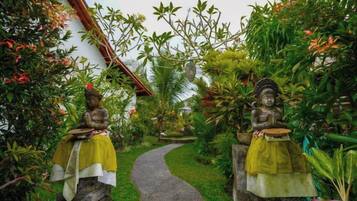 A pathway flanked by statues in a garden setting.