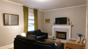 Een woonkamer met een open haard, een televisie en twee banken.