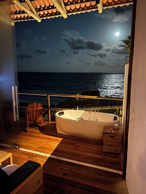 A balcony with a wooden floor, a wooden chair, and a white bathtub. - Pousada Mar no Olhar (Rio do Fogo)