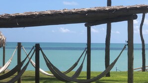 A thatched-roof structure with a hammock and rope barrier, overlooking a calm sea. - Pousada Mar no Olhar (Rio do Fogo)