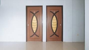 Two wooden doors with a leaf design, a white wall, and a tiled floor.