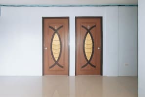 Two wooden doors with a leaf design, a white wall, and a tiled floor. - RedDoorz @ Raj Inn Guimaras (Jordan)