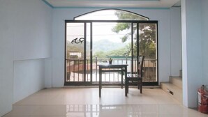 A room with a large sliding glass door leading to an outdoor area with a view of trees and a pool.